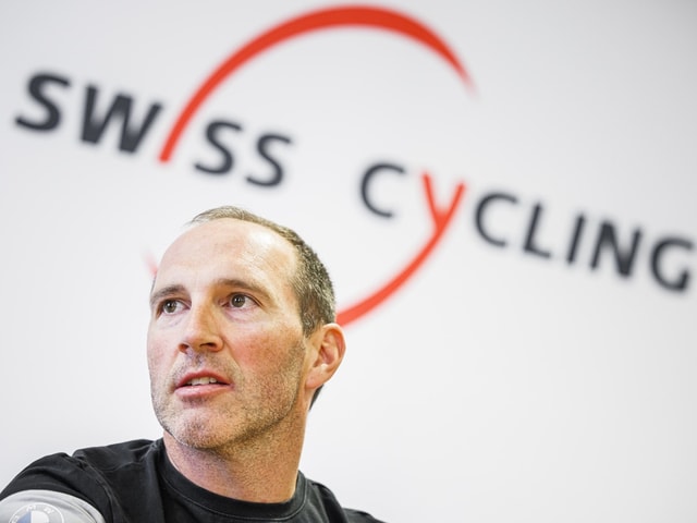 Mann vor Swiss Cycling Logo.