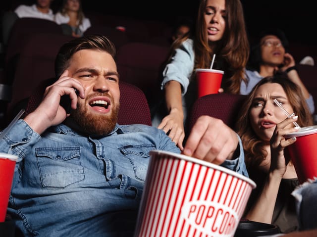 Ein Mann telefoniert im Kino, eine Frau reklamiert und eine Frau schaut geschockt.