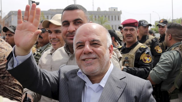 al-Abadi zwischen Soldaten mit zum Gruss erhobener Hand. 