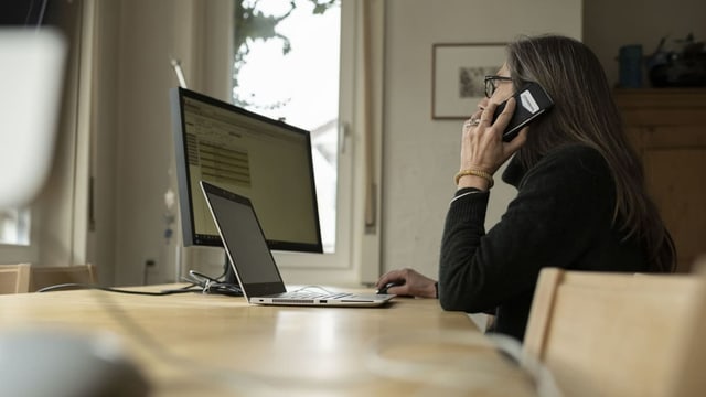 Frau telefoniert vor ihrem Laptop.