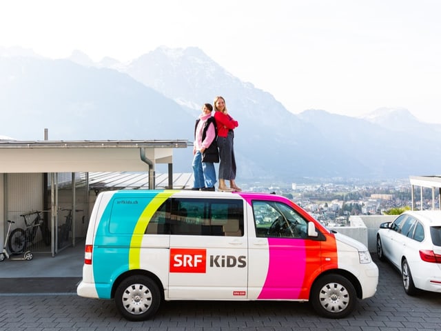 Anouk und Anna stehen auf dem SRF Kids Bus vor einer traumhaften Kulisse.