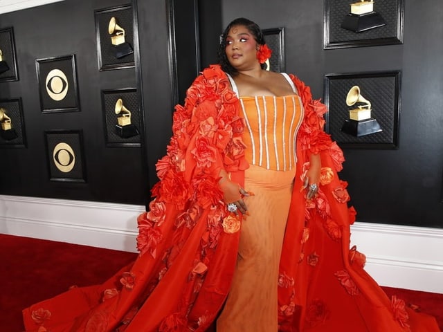 Sängerin Lizzo in einem gigantischen orangen Kleid, bestückt mit Rosen aus Stoff.