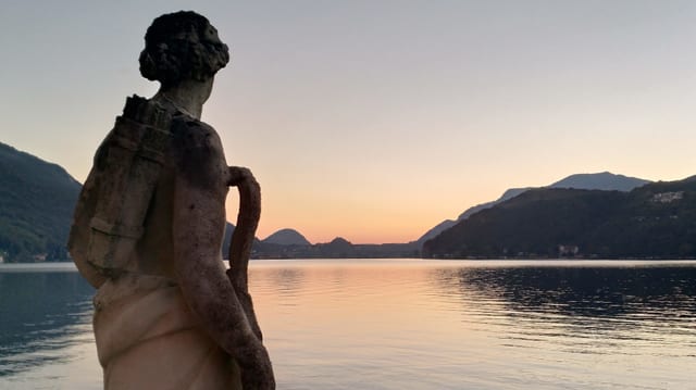 Eine Statue am See bei Abendstimmung.