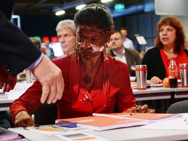 Frau mit Torte im Gesicht.