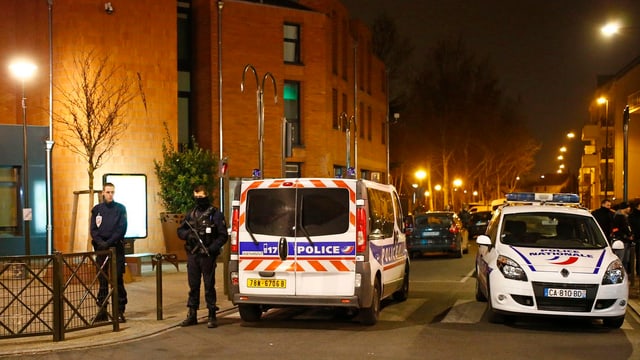 Polizeiautos und Beamte an einer Strasse.