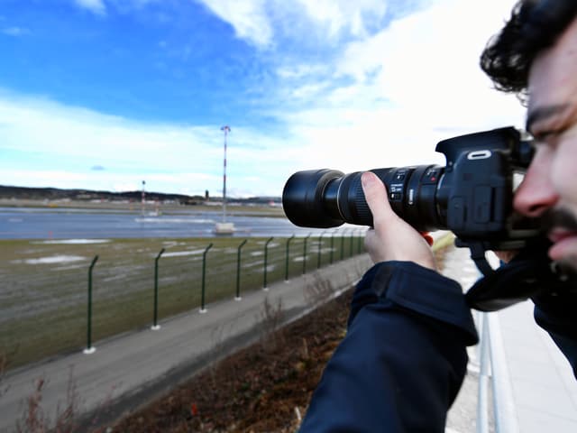 Mann mit Fotokamera mit grossem Objektiv.