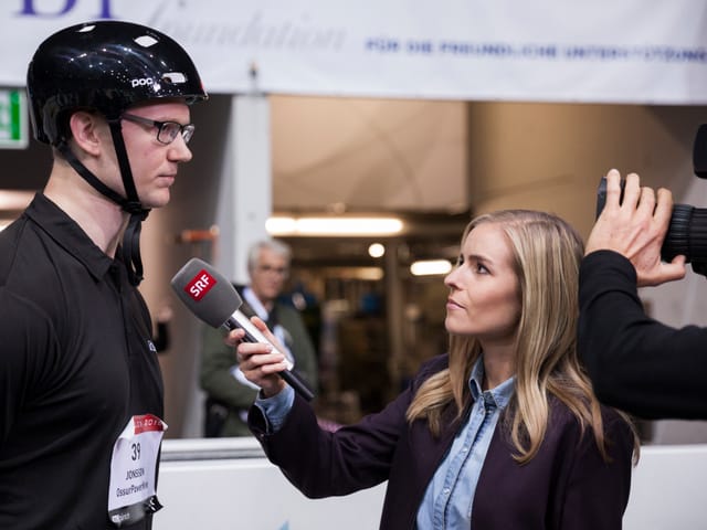 Moderatorin interviewt einen Teilnehmer am Cybathlon.