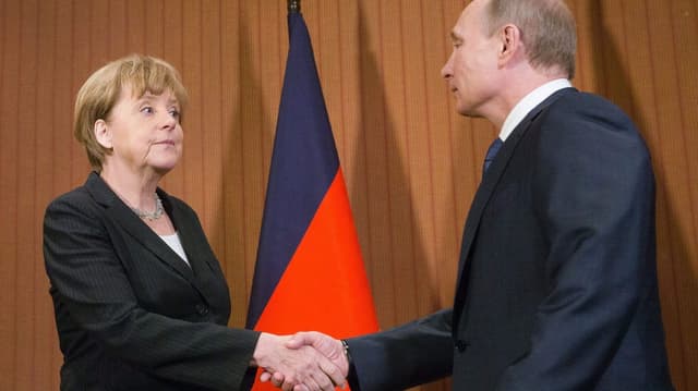 Merkel und Putin beim Händedruck, beide schauen genervt.