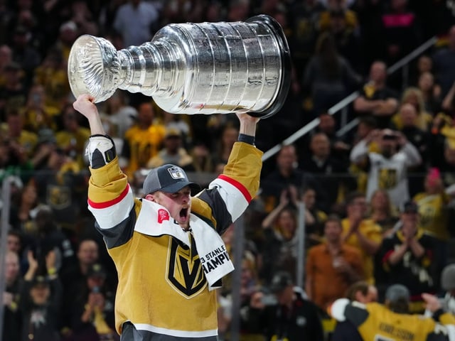 Eishockeyspieler hält den Stanley Cup über den Kopf.