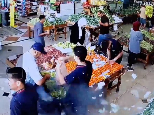 Kunden in einem belebten Supermarkt beim Einkaufen von Obst und Gemüse.