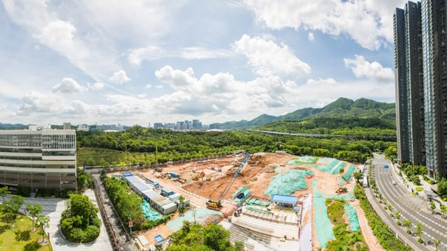 eine Baustelle umringt von Hochhäusern und Wald