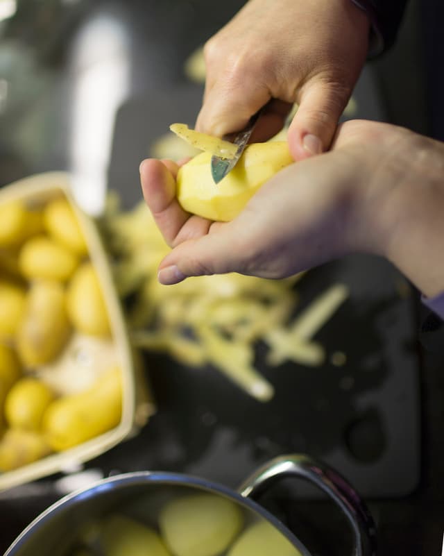 Eine Frau schält Kartoffeln.