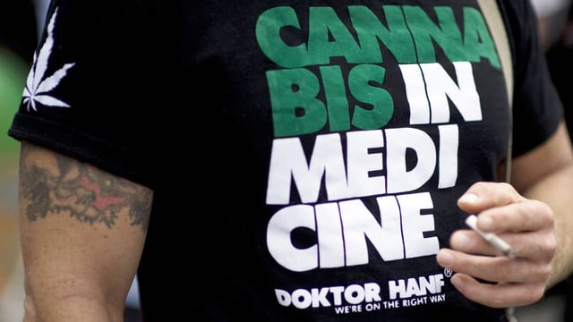 Ein Mann mit einem T-Shirt, auf dem für Cannabis in der Medizin geworben wird.