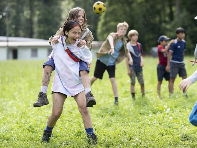 Pfadfinderinnen und Pfadfinder bei einem Ballspiel auf einer Wiese.