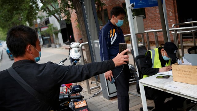 Der Fahrer eines Lieferdiensts präsentiert sein seine Gesundheitscode auf seinem Smartphone an einem Kontrollpunkt in Peking.