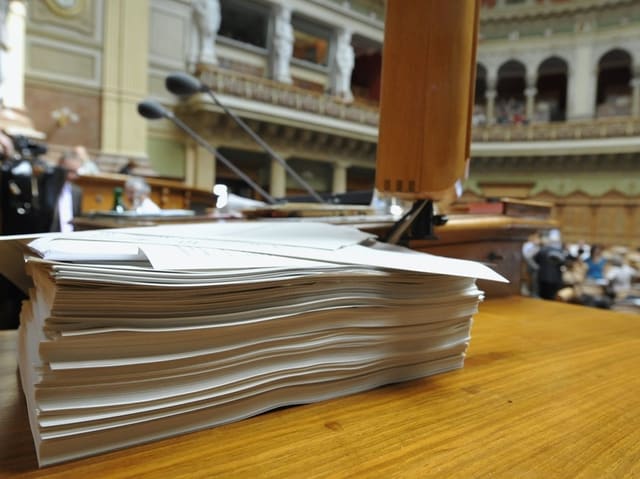 Grosser Stapel Papier auf einem Rednerpult im Parlament.