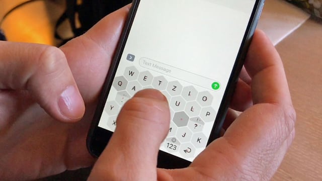 Mann schreibt auf wabenförmiger Handy-Tastatur.