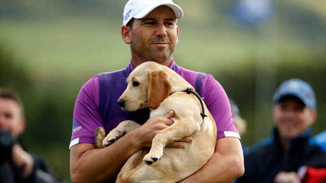 Ein Golfspieler hält einen Hund in den Armen.