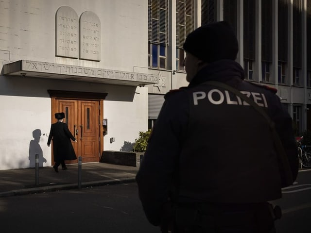 Ein Polizist schaut zu, wie ein orthodoxer Jude zur Synagoge läuft..