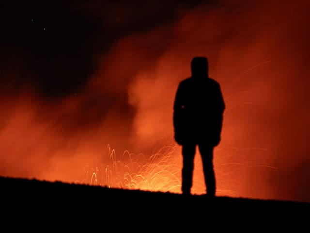 Silhouette eines Menschen vor rotem, rauchendem Hintergrund.