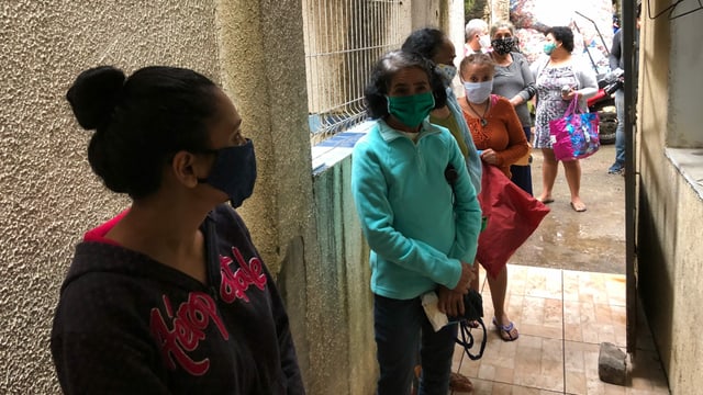 Frauen mit Maske stehen in einer Reihe.