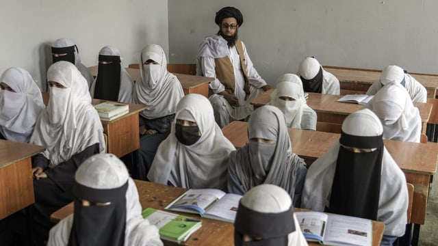 Verschleiderte Mädchen in einem Schulzimmer mit Lehrer.