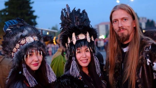 Zwei Tuwinerinnen und ein Tuwiner posieren in ihrer traditionellen Kleidung am Chomej-Festival.