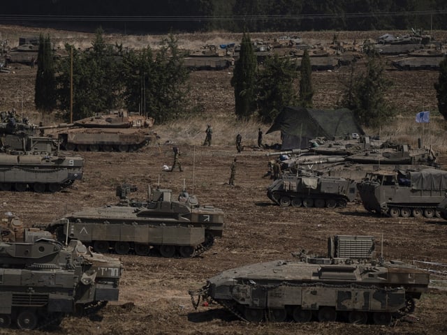 Panzer und Soldaten auf einem Feld.