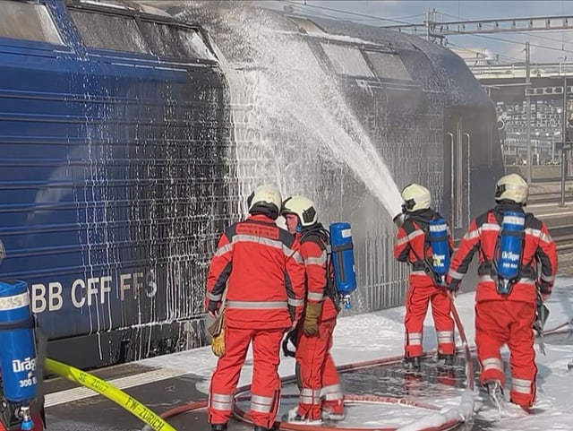 Feuerwehrmänner löschen die Lok.