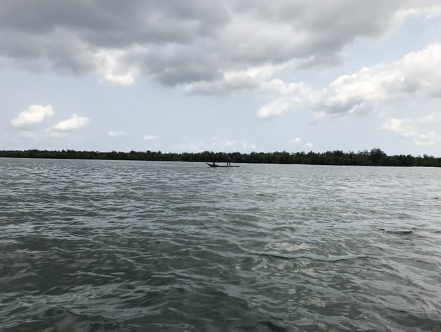 Ein Fischerboot mit zwei Personen auf einem Fluss.