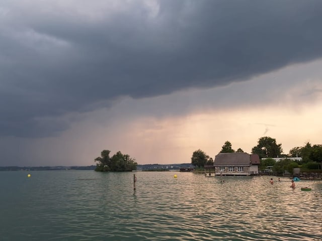 Haus am Seeufer unter bewölktem Himmel.