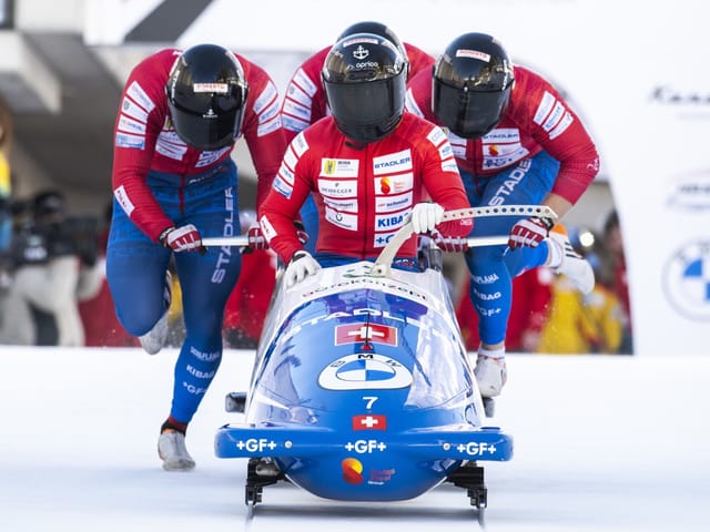 Bobteam in rot-blauer Uniform startet Rennen.