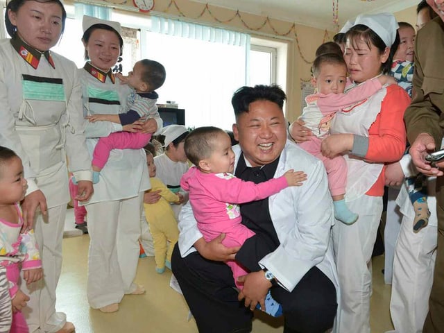 Diktator Kim Jong Un besucht ein Spital für Soldatenkinder und hält einen kleinen Bub auf den Knien.