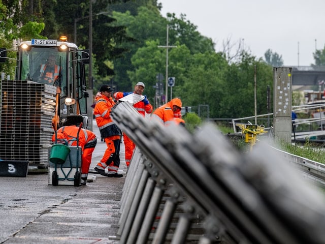 Bauarbeiter in orangefarbener Kleidung arbeiten an einer Strasse.