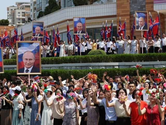 Menschen jubeln mit Plakaten von Putin. 