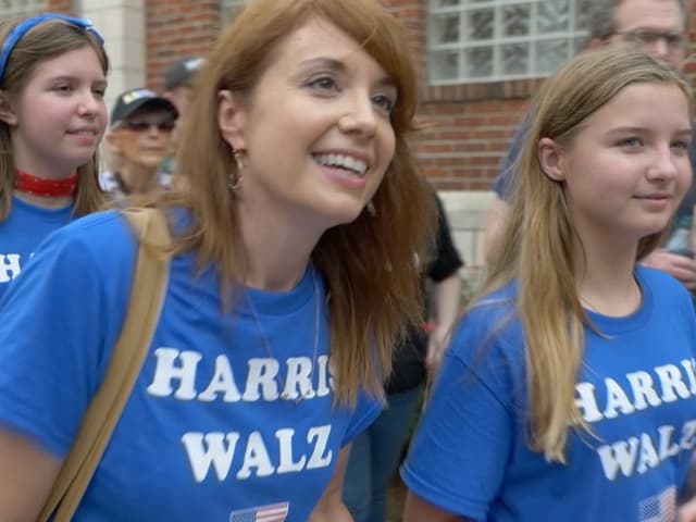 Drei Frauen in blauen T-Shirts mit Aufdruck bei einer Versammlung.