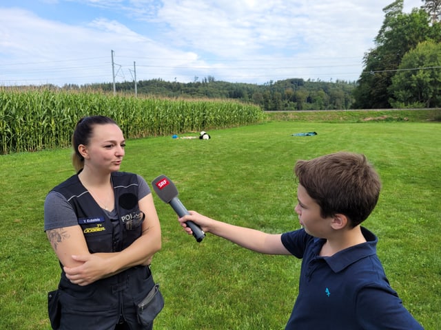 Yvonne wird von Lenny mit dem Mikrofon in der Hand interviewt. Sie stehen auf der Trainingswiese.