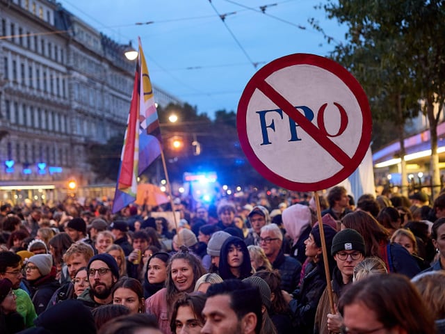 Menschenmenge bei Demonstration mit Protestplakat gegen FPÖ.