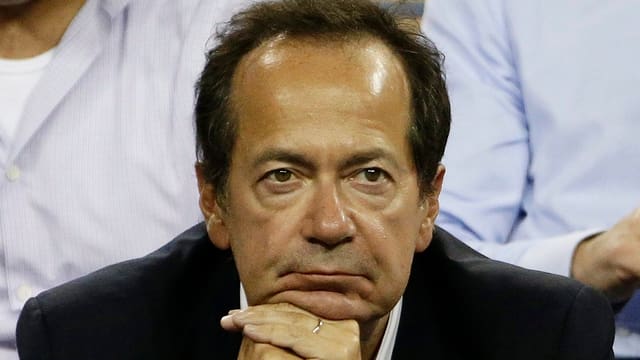 John Paulson stützt sich nachdenklich auf seine Hände.