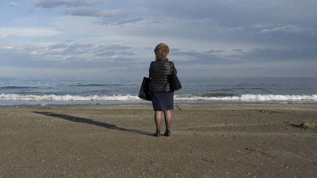 Frau steht am Meer