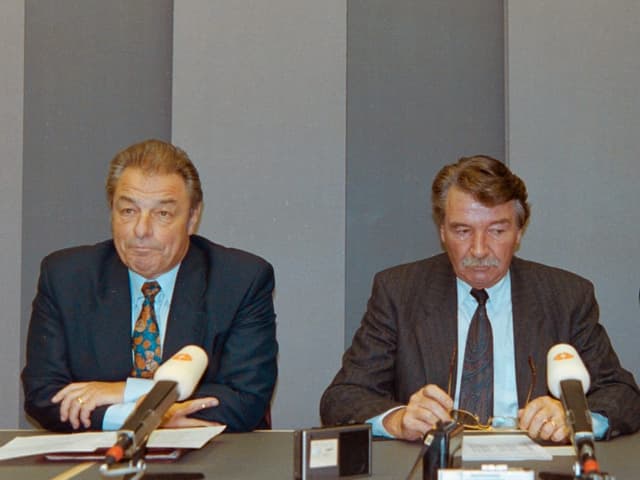 Die beiden alt Bundesräte sitzen nebeneinander und machen lange Gesichter. 