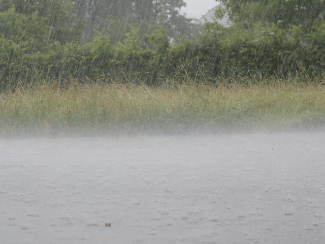 Starker Regenfall prallt auf Asphalt.