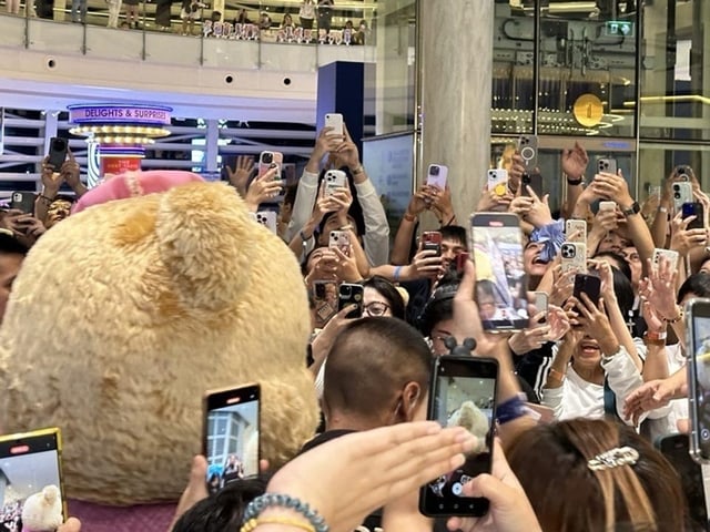 Maskottchen Butterbear läuft durch eine Menschenmenge wobei viele Handys das Maskottchen filmen