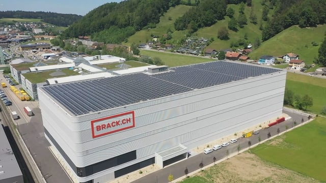 EIn grosses graues Gebäude im Vordergrund und dahinter mehrere flache, aber grosse Hallen.