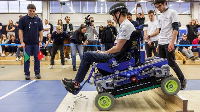 Ein Rollstuhlfahrer überwindet ein treppenartiges Hindernis.