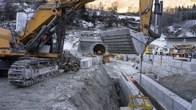 Grosse Baustelle beim Tunneleingang. Ein schwerer Bagger bringt Gestein weg.