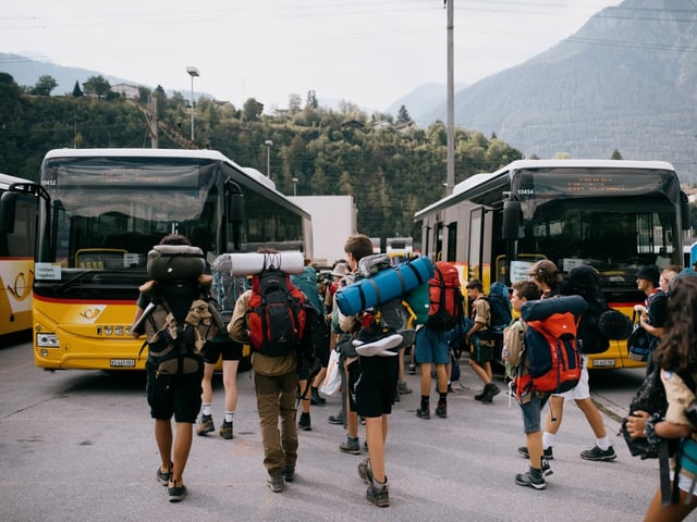 Pfadfinder:innen laufen mit Rucksack bepackt zum Postauto. 