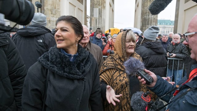 Zwei Frauen auf einer Demo werden von einem Reporter interviewt.