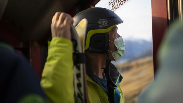 Man mit Ski in Seilbahn