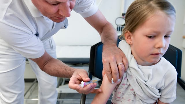 Kinderarzt verpasst Kind eine Spritze in den Arm